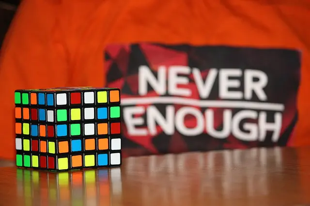 Colorful rubik 's cube sits in front of a red shirt that says never enough