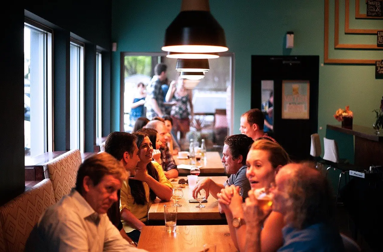 a group sitting at a restaurant interacting and there are drinks sitting on the table