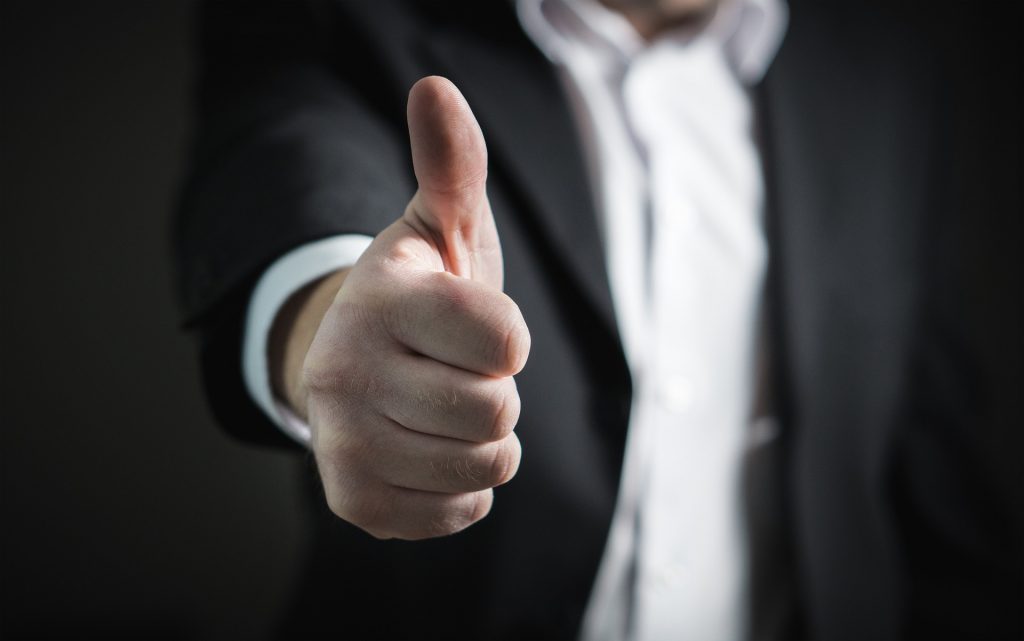 a man in a suit is giving a thumbs up