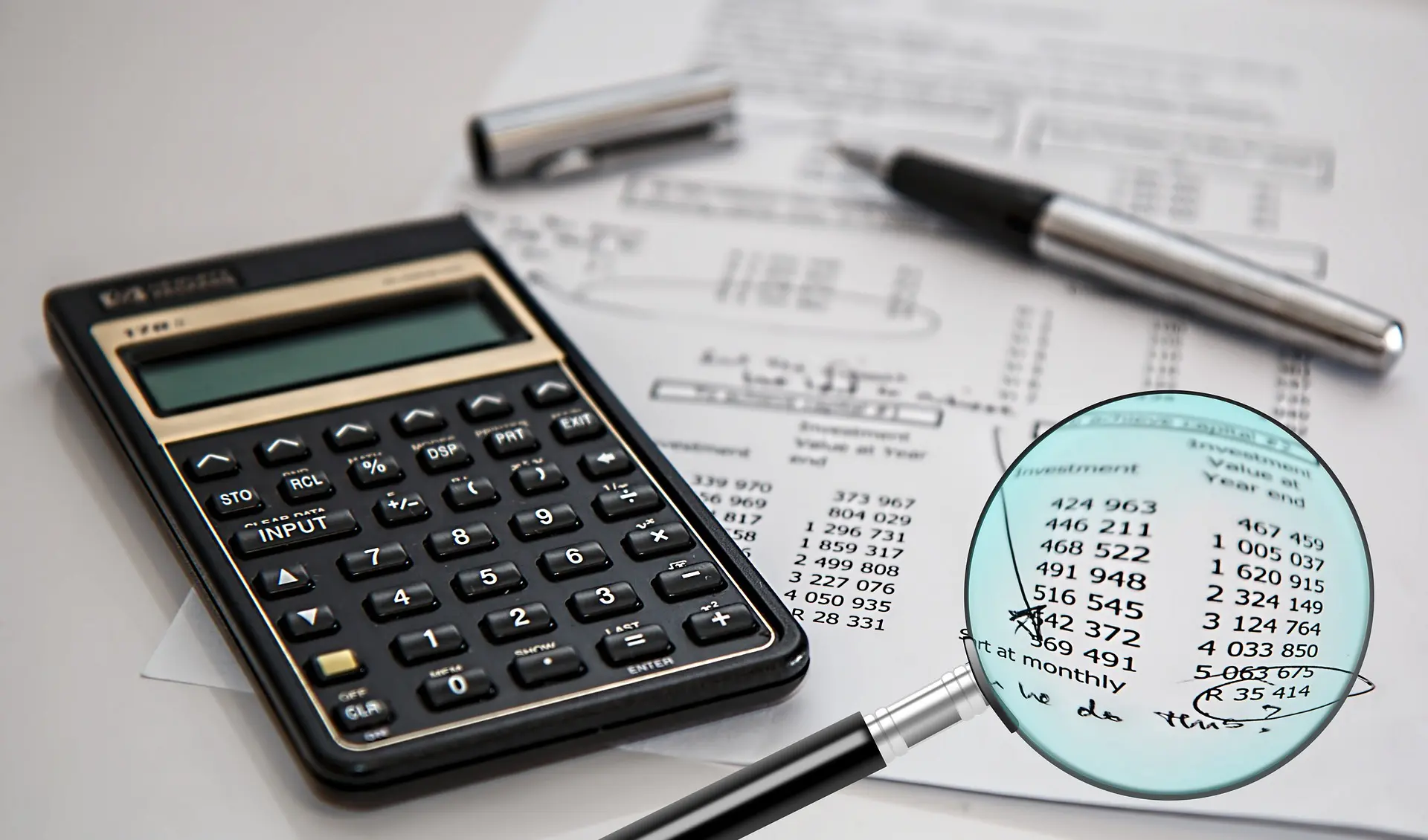 a calculator sits on top of a piece of paper next to a magnifying glass