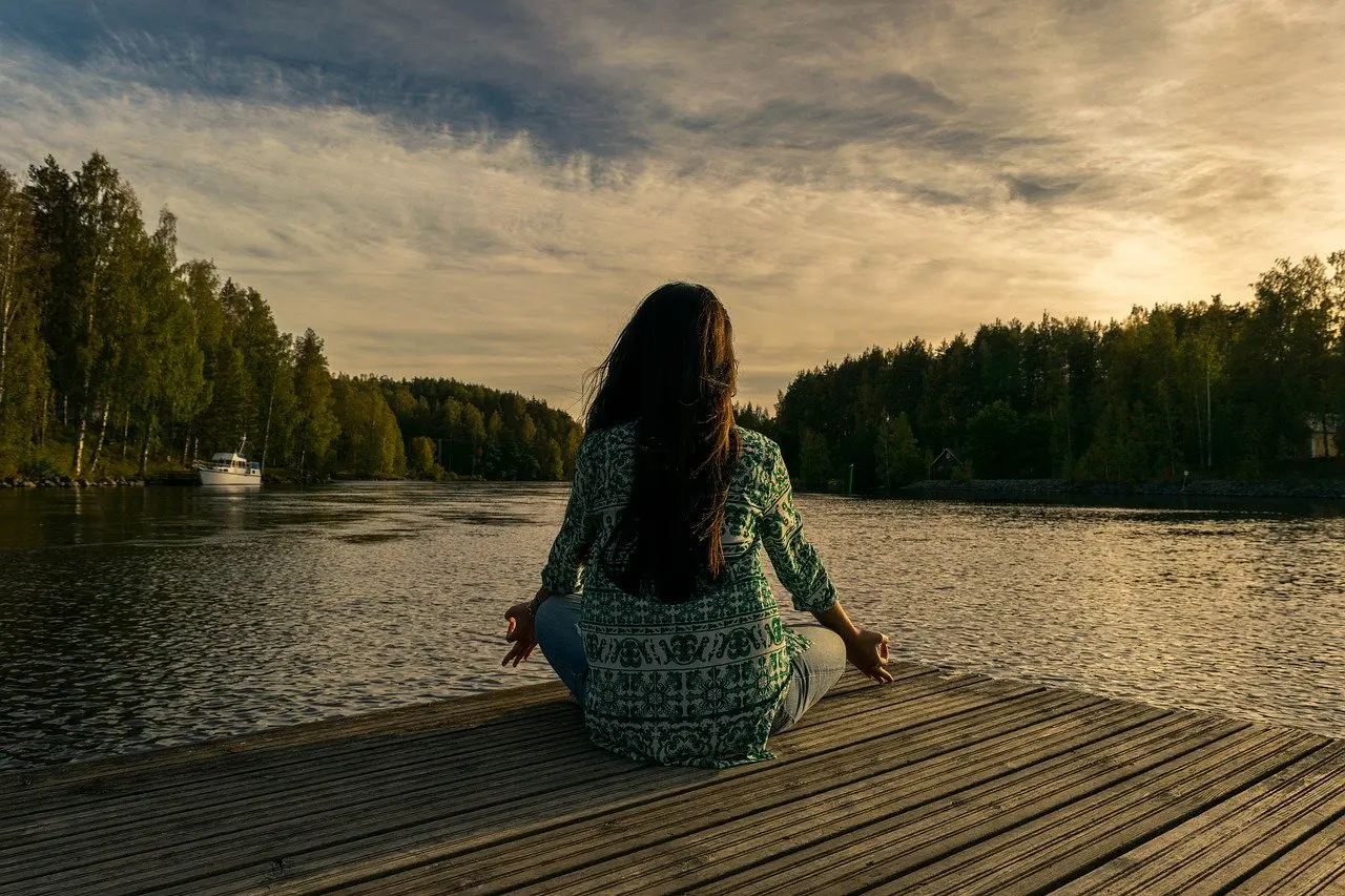 a woman sits on a dock looking at a body of water