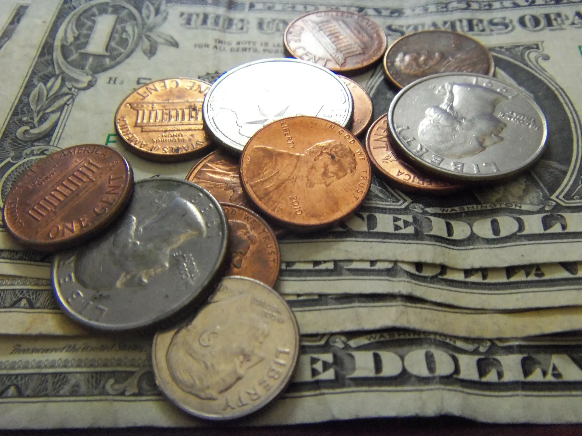 pile of coins on top of a one dollar bill