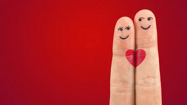 Couple of fingers with smiley faces and a heart painted on them
