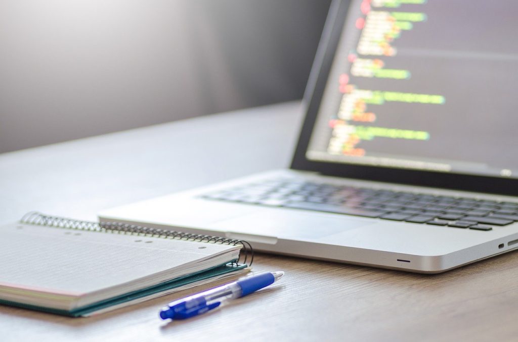 a notebook and pen sitting in front of an open computer