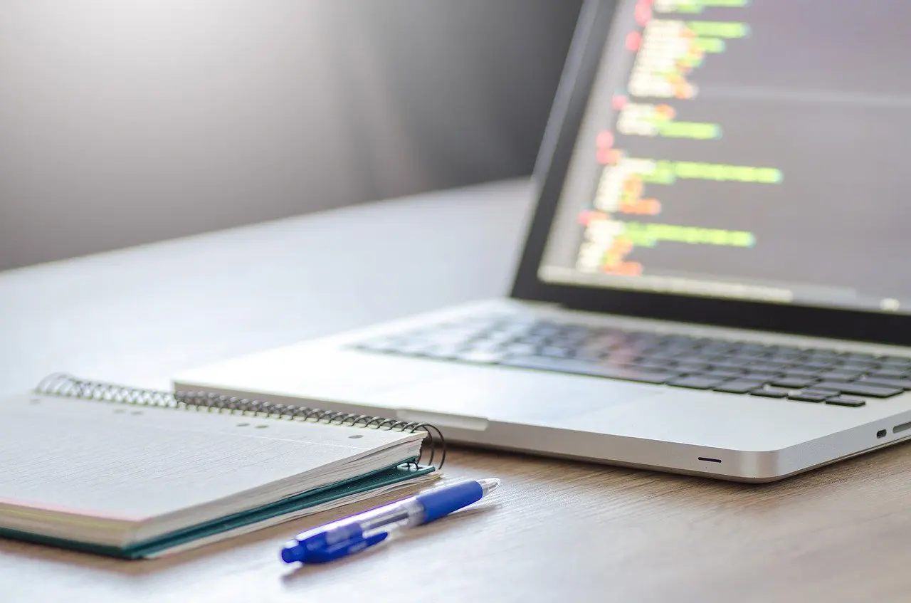 a notebook and pen sitting in front of an open computer
