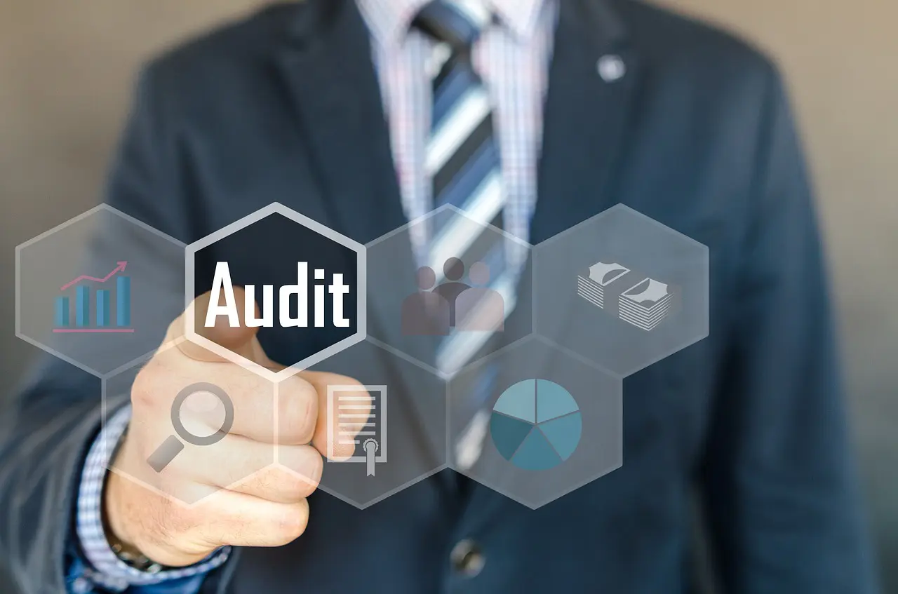 a man is pointing at a screen that says audit