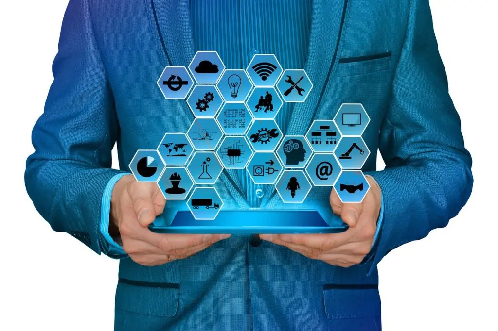 an individual's hands holding a tablet displaying an array of icons