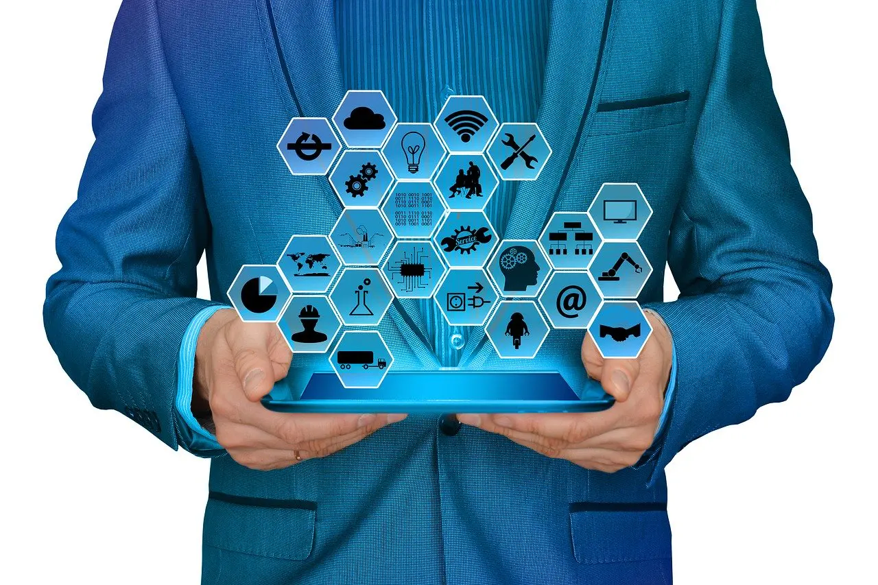 an individual's hands holding a tablet displaying an array of icons