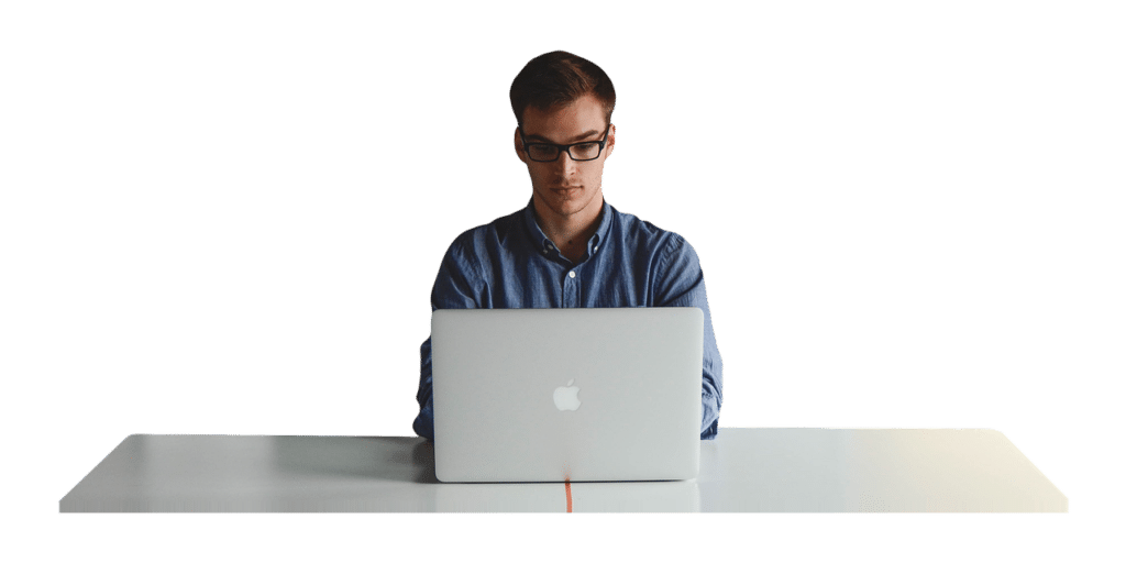 a man is sitting at a desk using an apple laptop