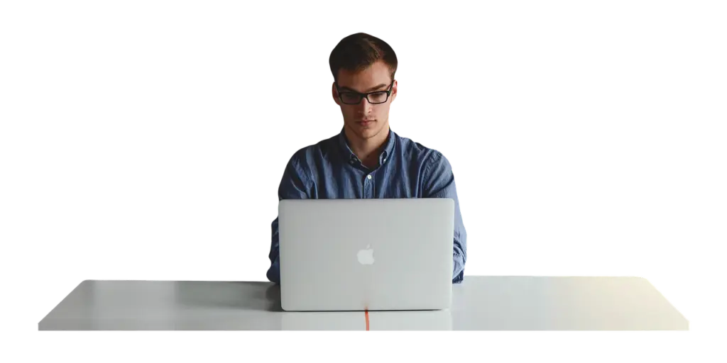 a man is sitting at a desk using an apple laptop