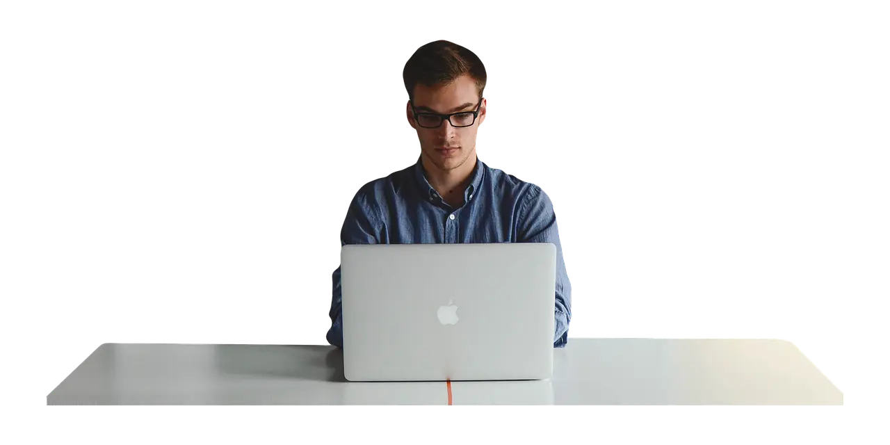 a man is sitting at a desk using an apple laptop