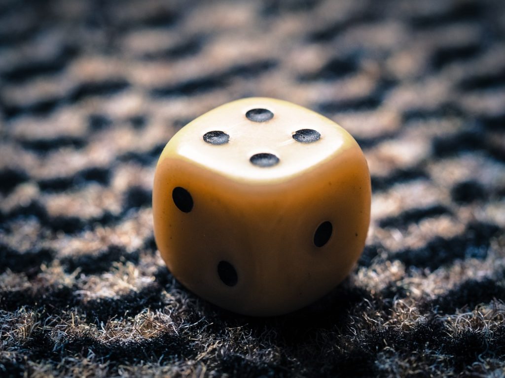 Closeup of yellow dice with four black dots on the top