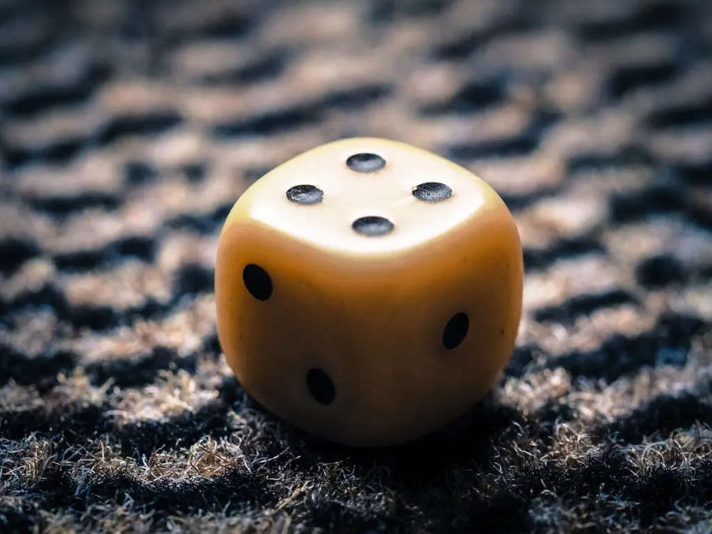 Closeup of yellow dice with four black dots on the top