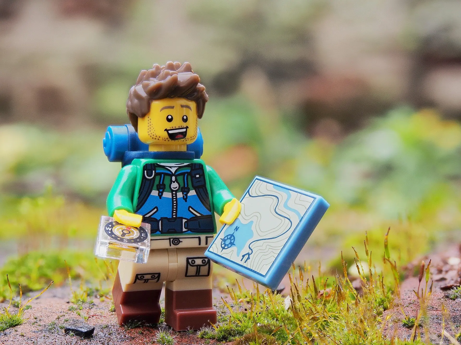 lego figure holding a map and a compass
