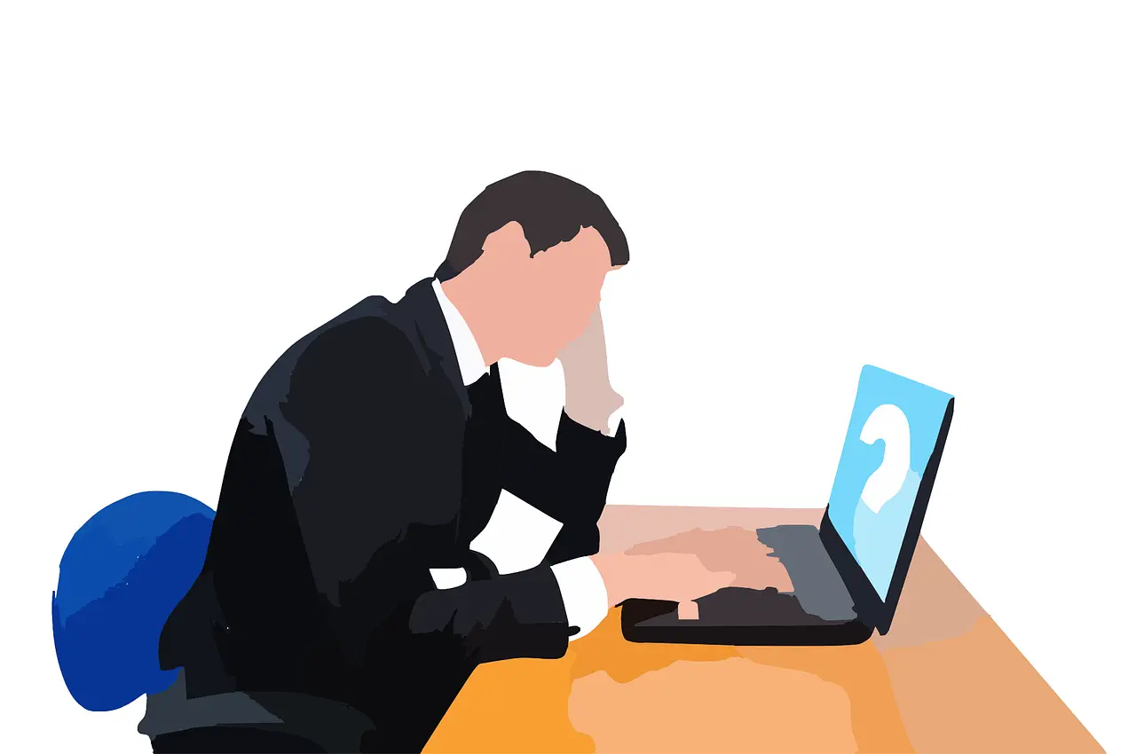 a man in a suit sits at a desk using a laptop