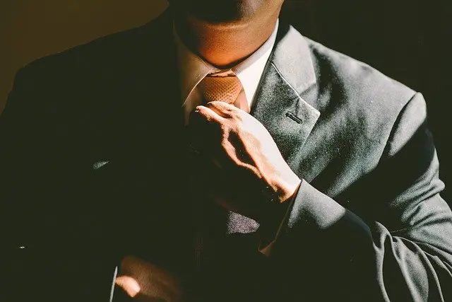 a man in a suit and tie is adjusting his tie