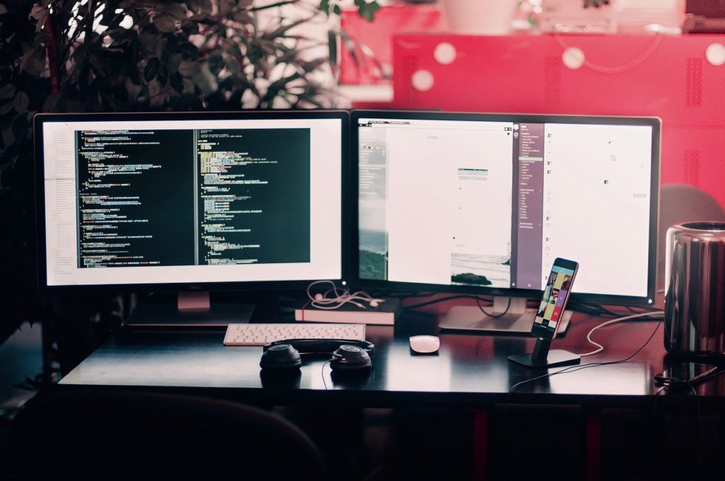 two computer monitors on a desk with one that says ' slack ' on it