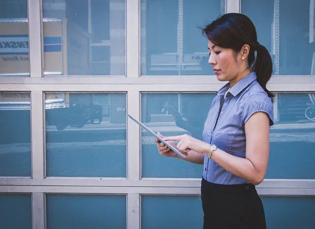 woman is standing in front of a garage door using a tablet computer