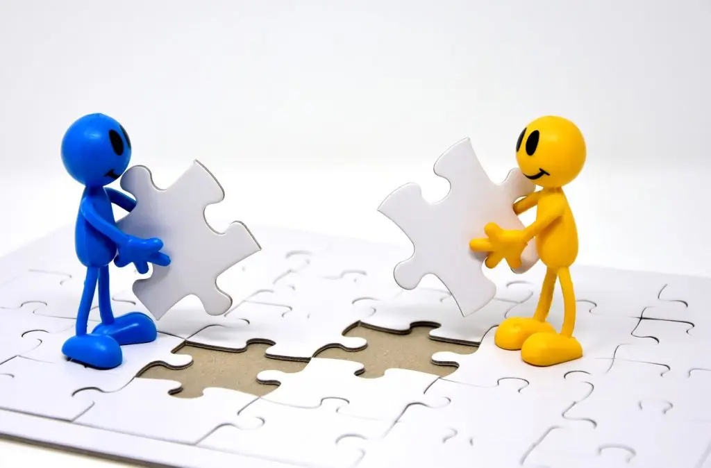 two blue and yellow figurines are putting puzzle pieces together