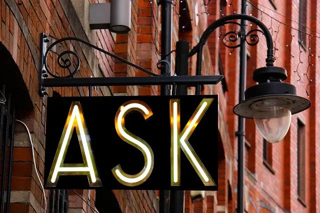a neon sign that says ask is hanging from a street light