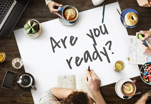 a group of people are sitting around a table with a sign that says " are you ready "