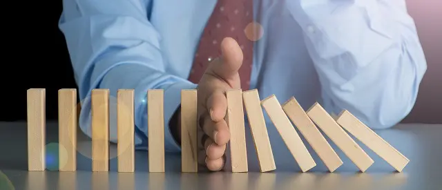 a man is stopping a row of wooden blocks from falling on a table