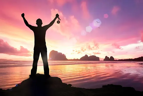 Silhouette of a man holding a medal in front of the ocean