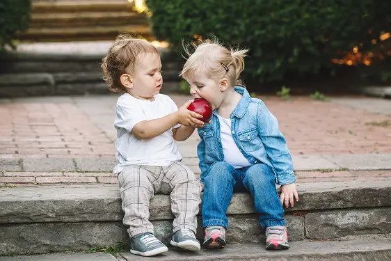 boy and a girl are sitting on steps eating apples