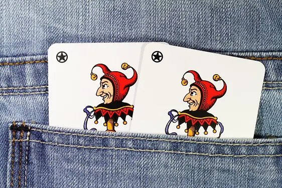 a pair of joker playing cards sticking out of a pocket