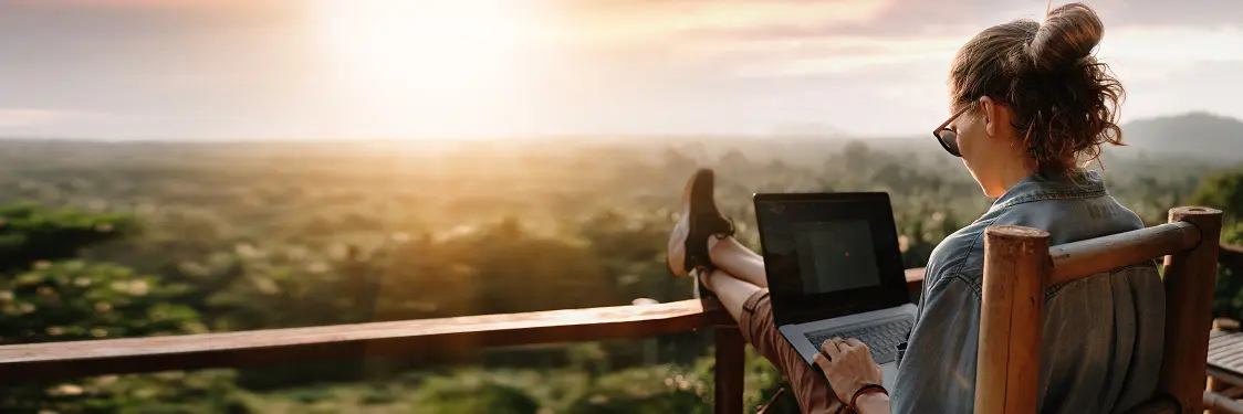 a woman is sitting on a balcony using a laptop computer