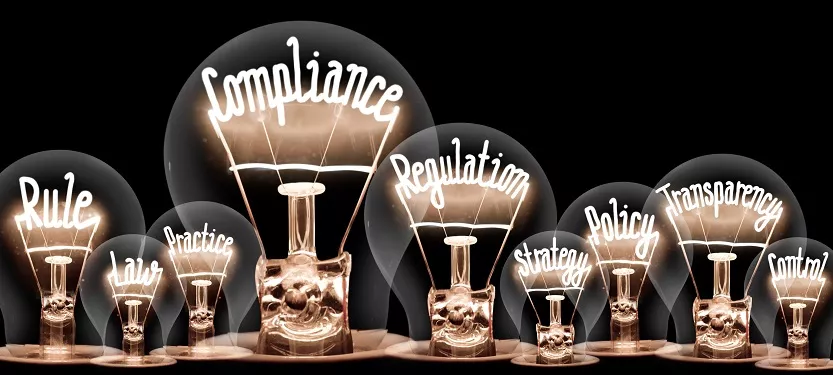 numerous light bulbs all featuring different words inside the light bulbs, like 'compliance', 'regulation', and 'transparency'