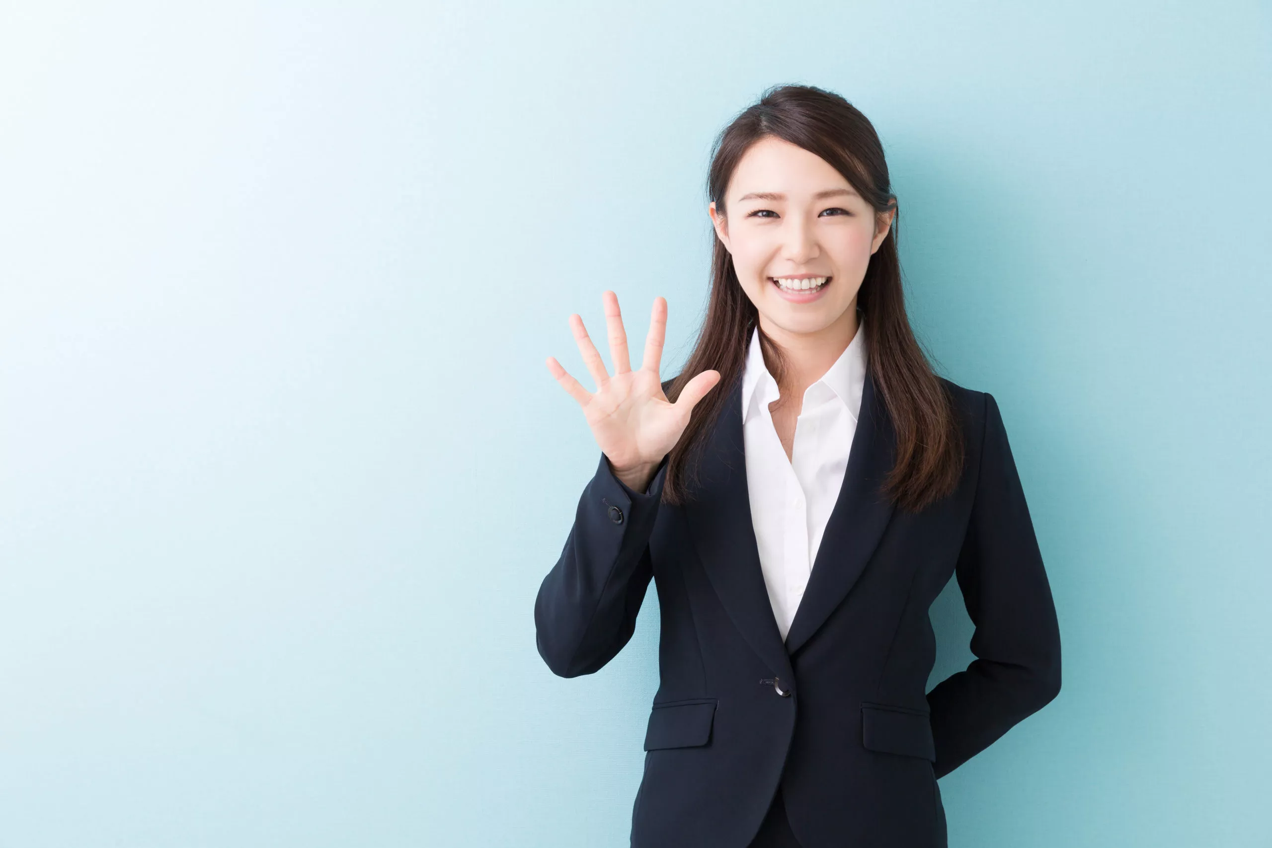 a woman in a suit and white shirt holds up five fingers