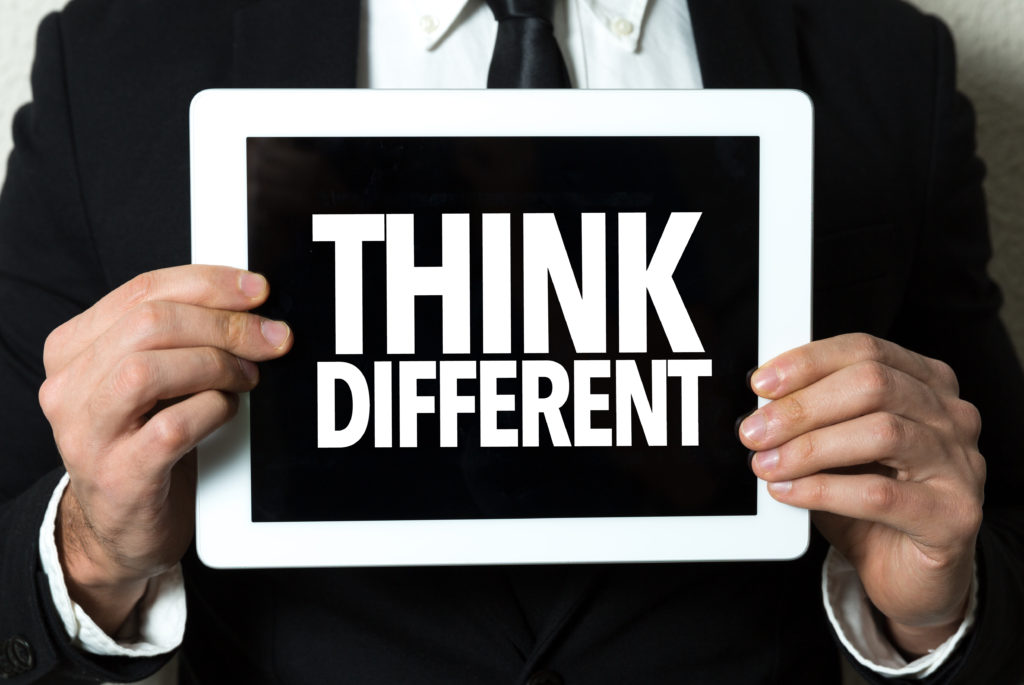 a pair of hands is holding a sign that reads 'think different'