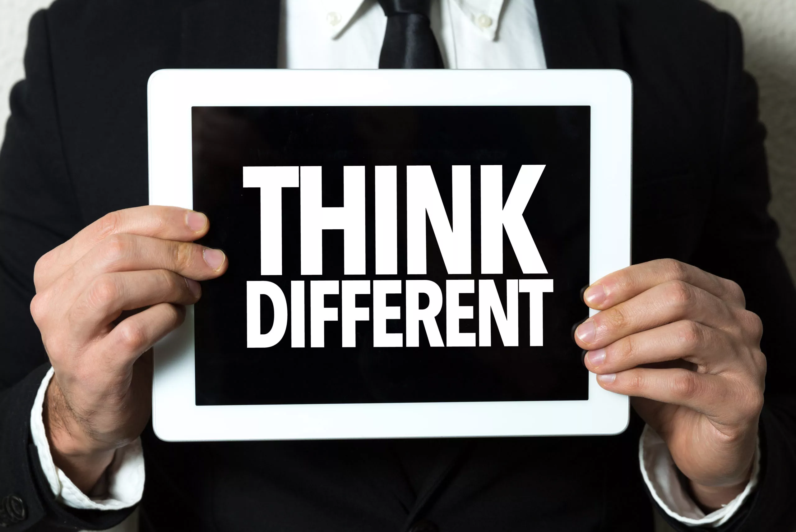 a pair of hands is holding a sign that reads 'think different'