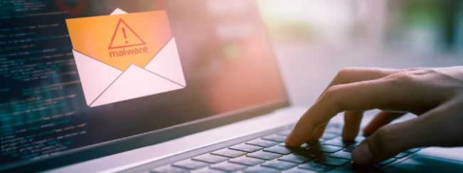 a person is typing on a laptop with an envelope that says malware on it